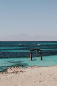 Peaceful beach scene with a swing over turquoise waters in Hurghada, Egypt.